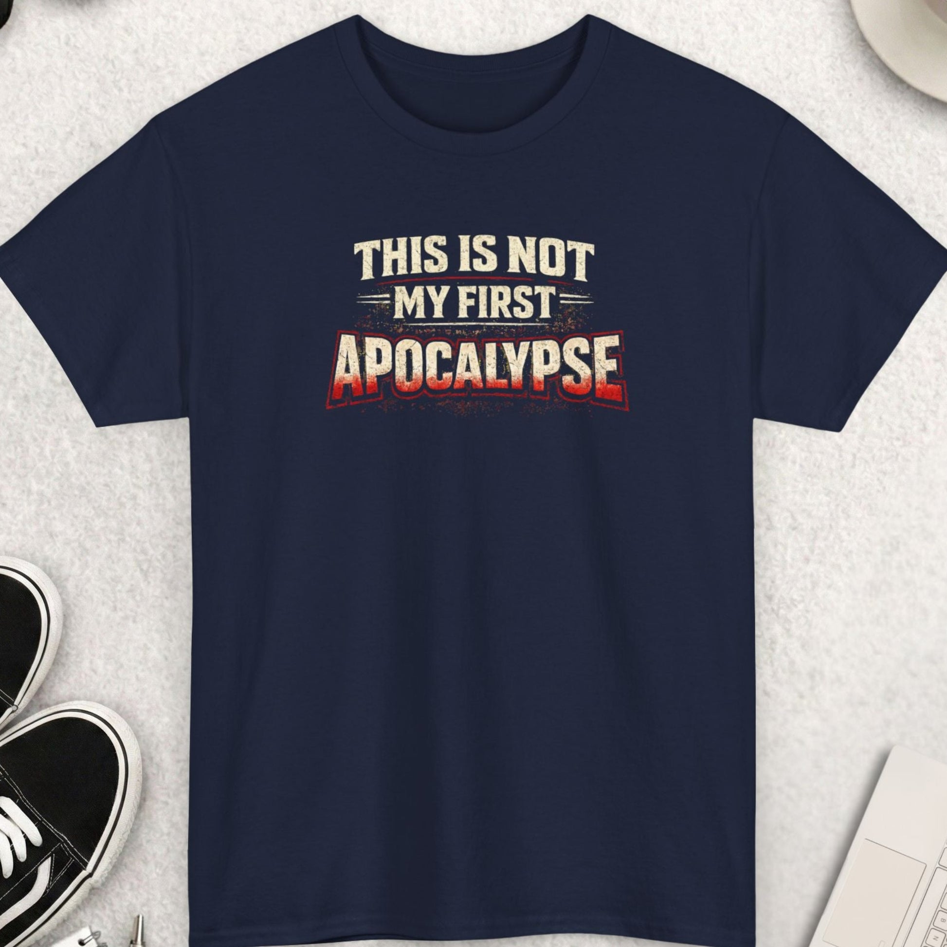 Navy blue graphic t-shirt featuring distressed text that reads “This Is Not My First Apocalypse” in white and red lettering, centered on the chest.