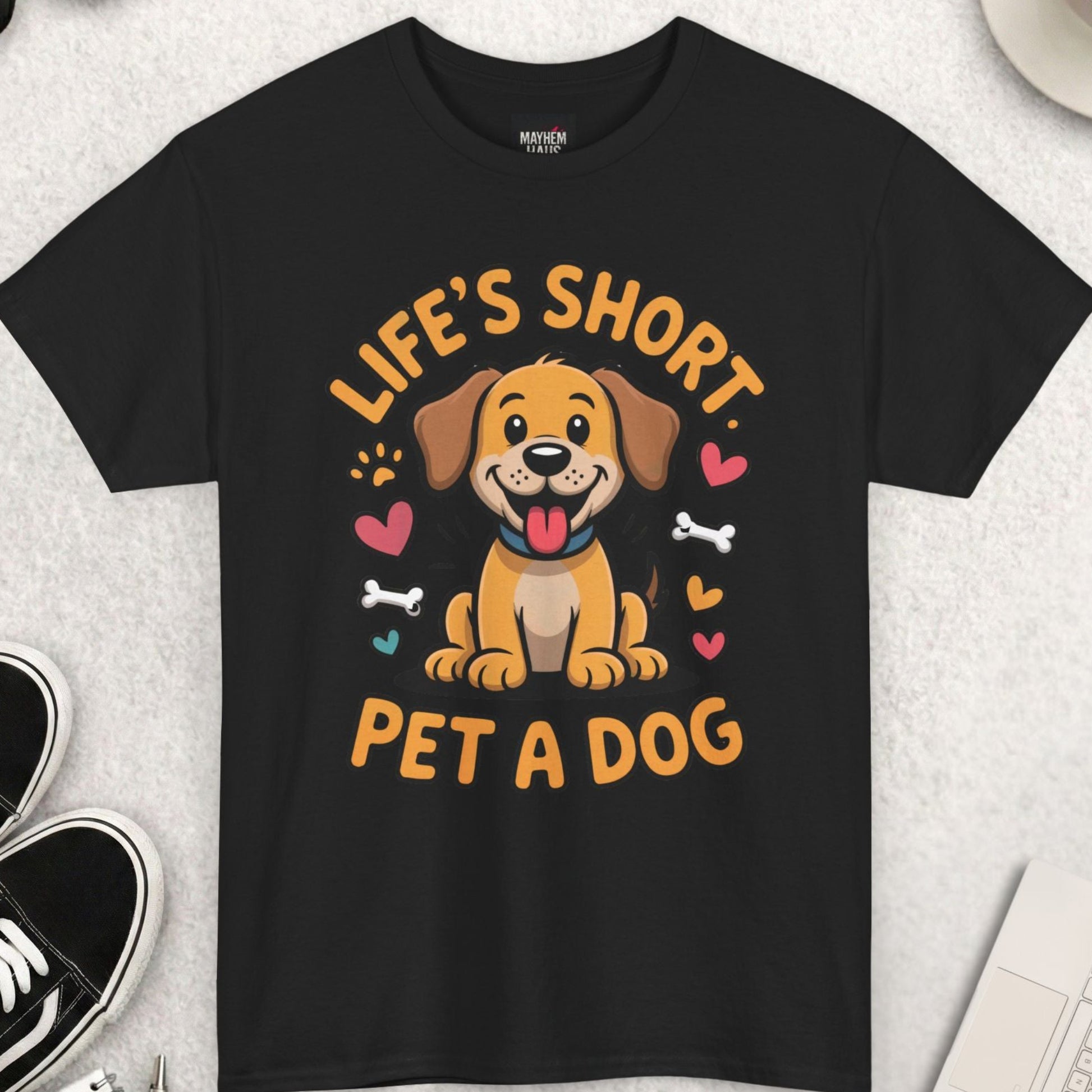 Black t-shirt with a dog graphic and text on a light gray surface with accessories.
