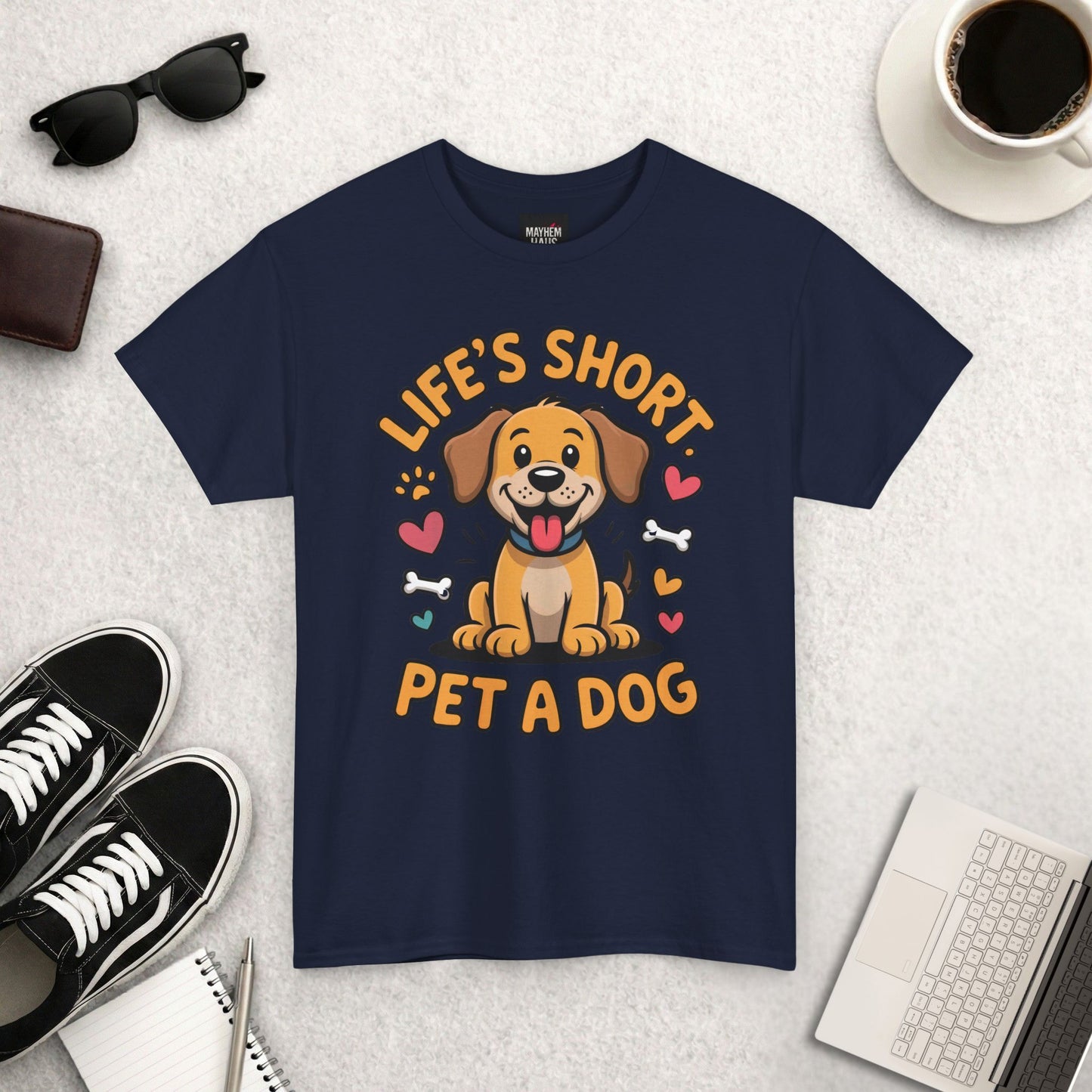 Navy blue t-shirt with a dog graphic and text on a light gray surface with accessories.