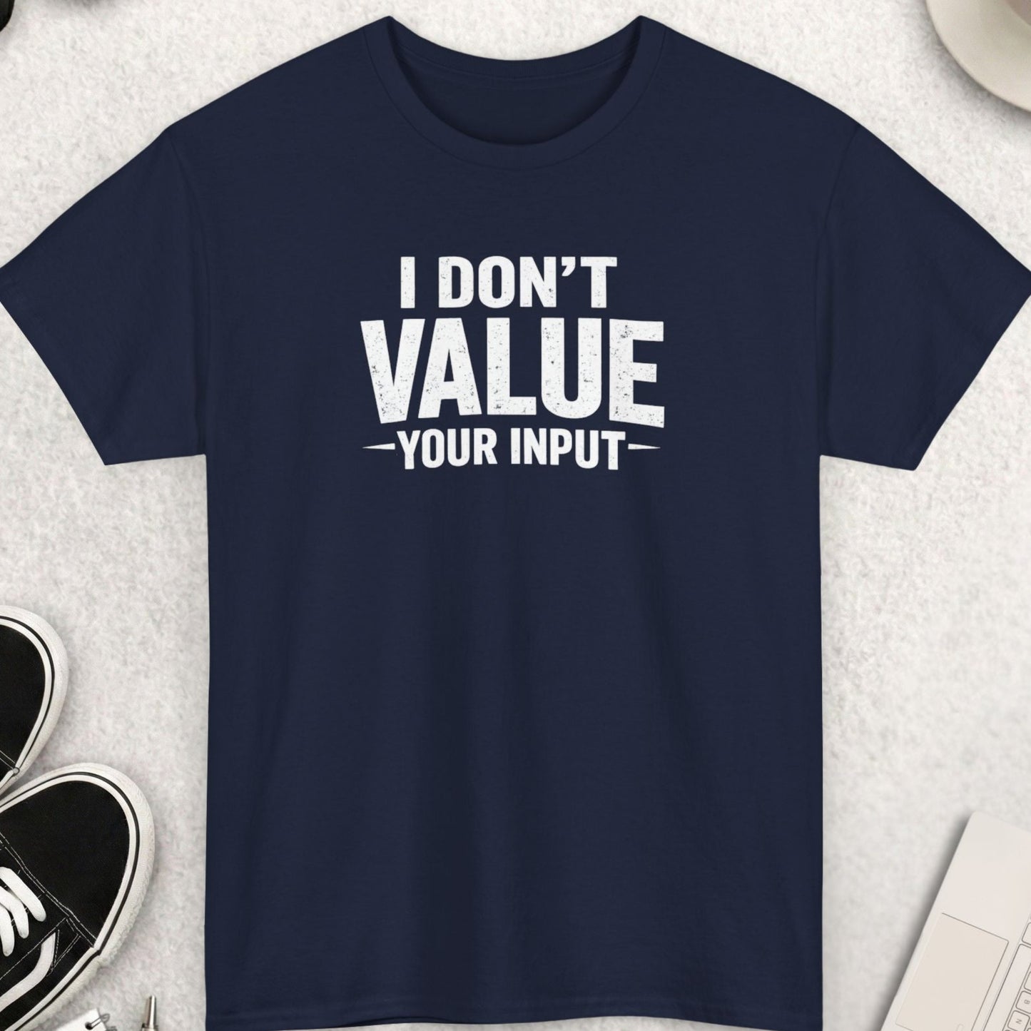 Navy blue t-shirt with 'I Don't Value Your Input' text on a light gray surface with accessories.