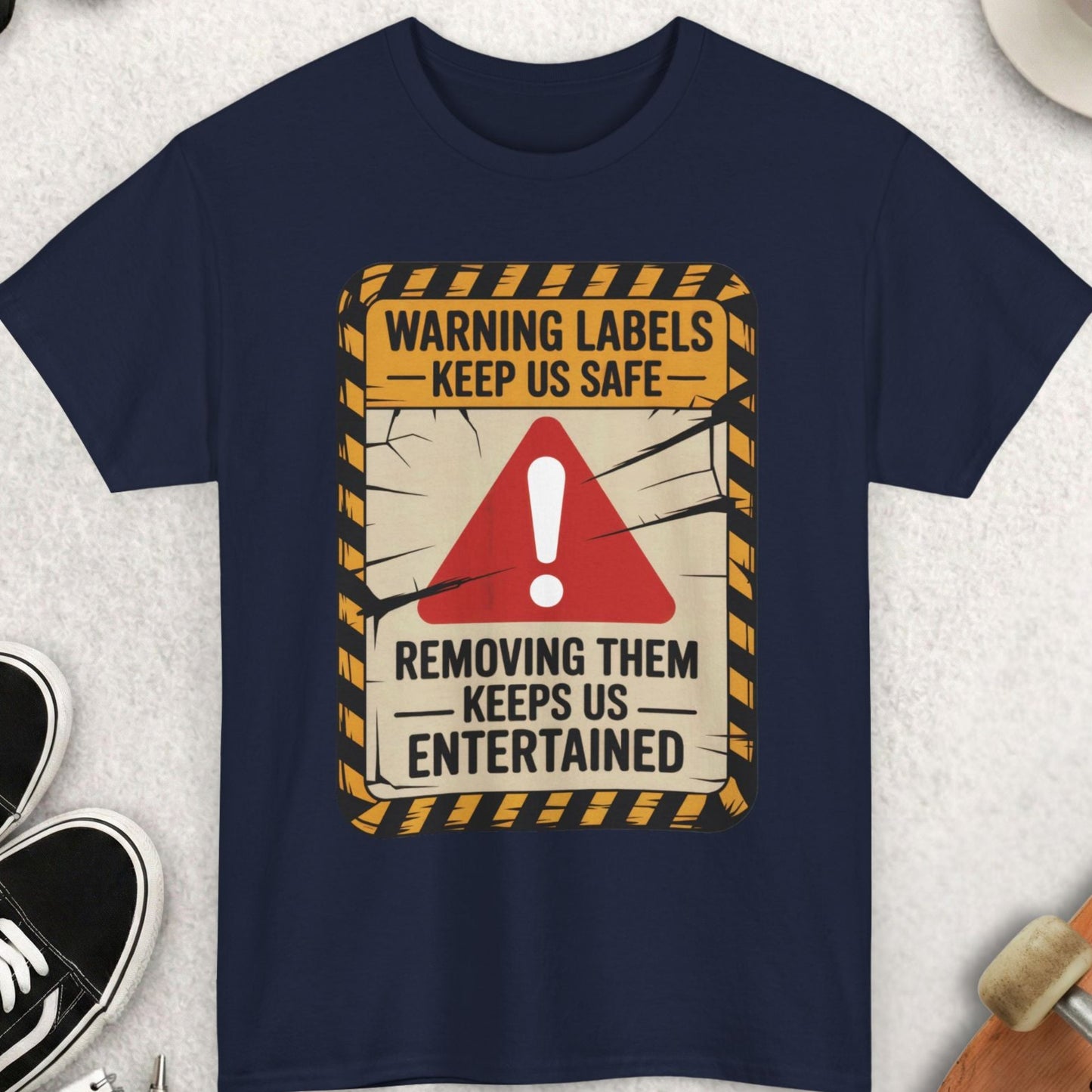 Navy blue t-shirt with a humorous warning label design on a light gray surface with accessories.