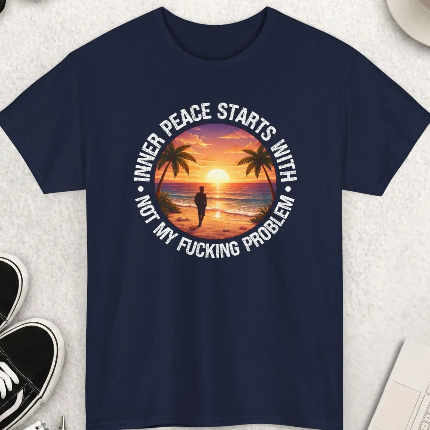 Navy blue t-shirt with a graphic design and text on a light gray surface with accessories.
