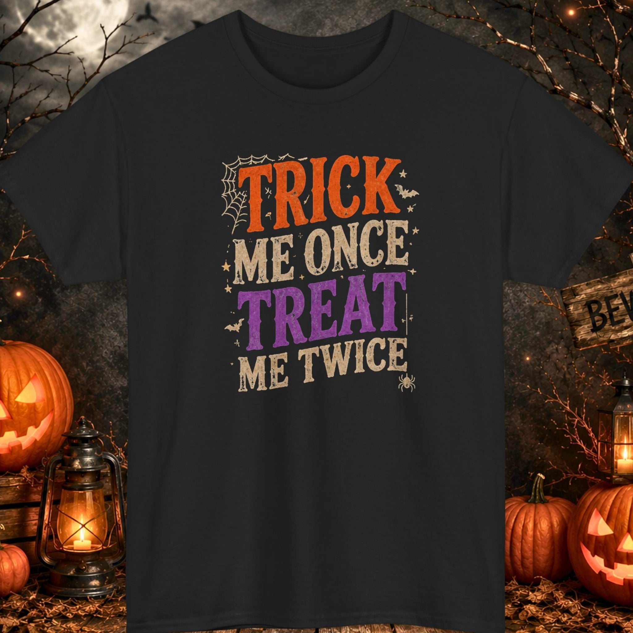 Mayhem Haus black Halloween T-shirt featuring the phrase "Trick Me Once, Treat Me Twice" in distressed orange, purple, and cream vintage typography with spiderweb, bat, and spider graphics.