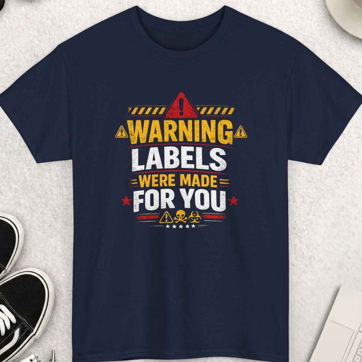 Navy blue t-shirt with a humorous graphic design on a light gray surface with accessories.
