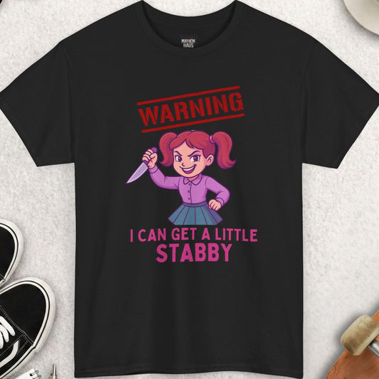 Black t-shirt with graphic design and text on a light gray surface with accessories.