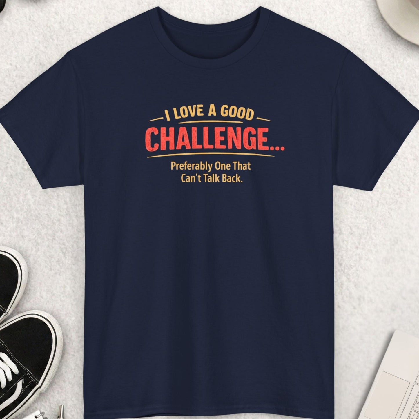 Navy Bluet-shirt with humorous text design on a light gray surface with accessories.