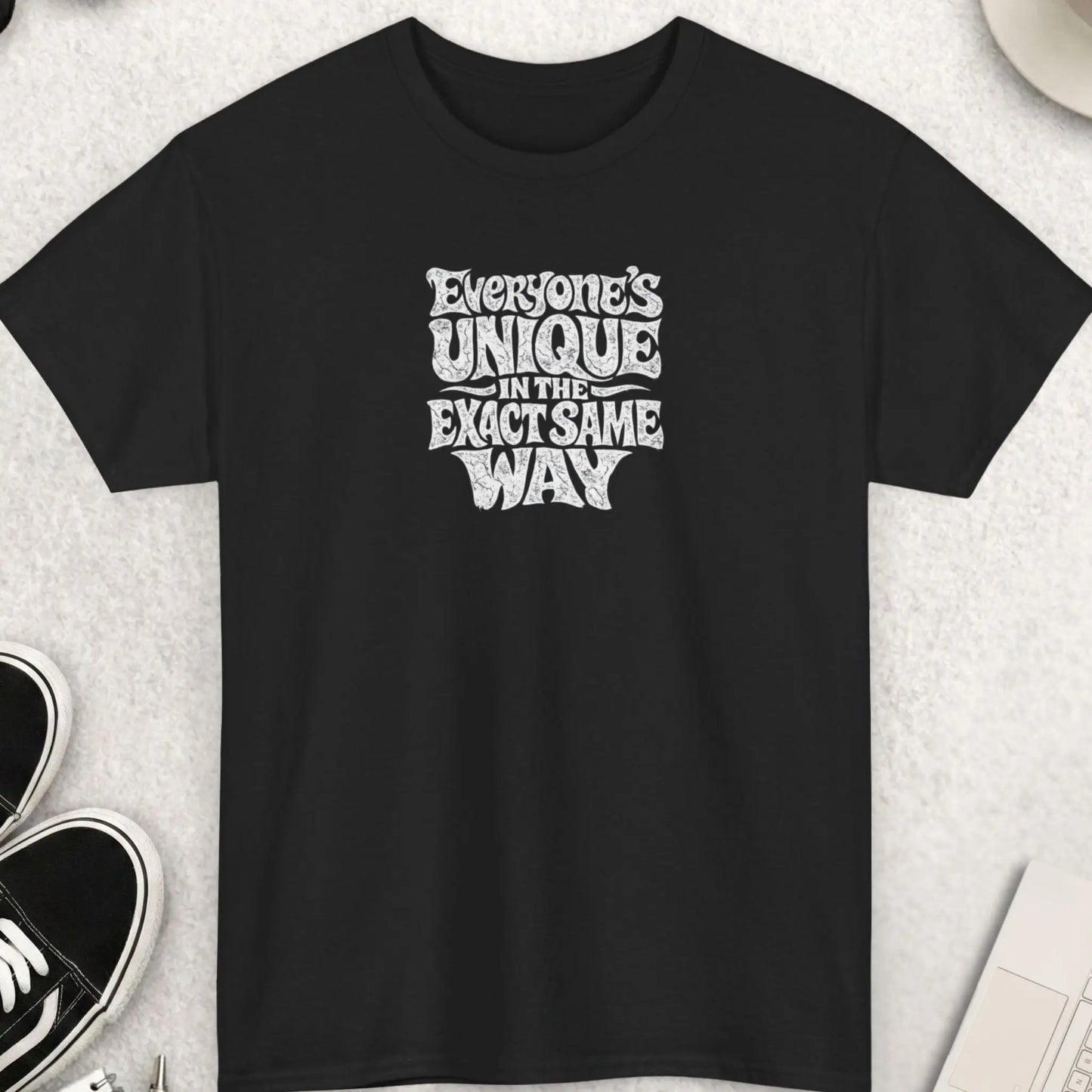 Black distressed typography graphic t-shirt featuring the phrase “Everyone’s Unique In The Exact Same Way” in warped vintage white lettering with a grunge-inspired alternative streetwear aesthetic.