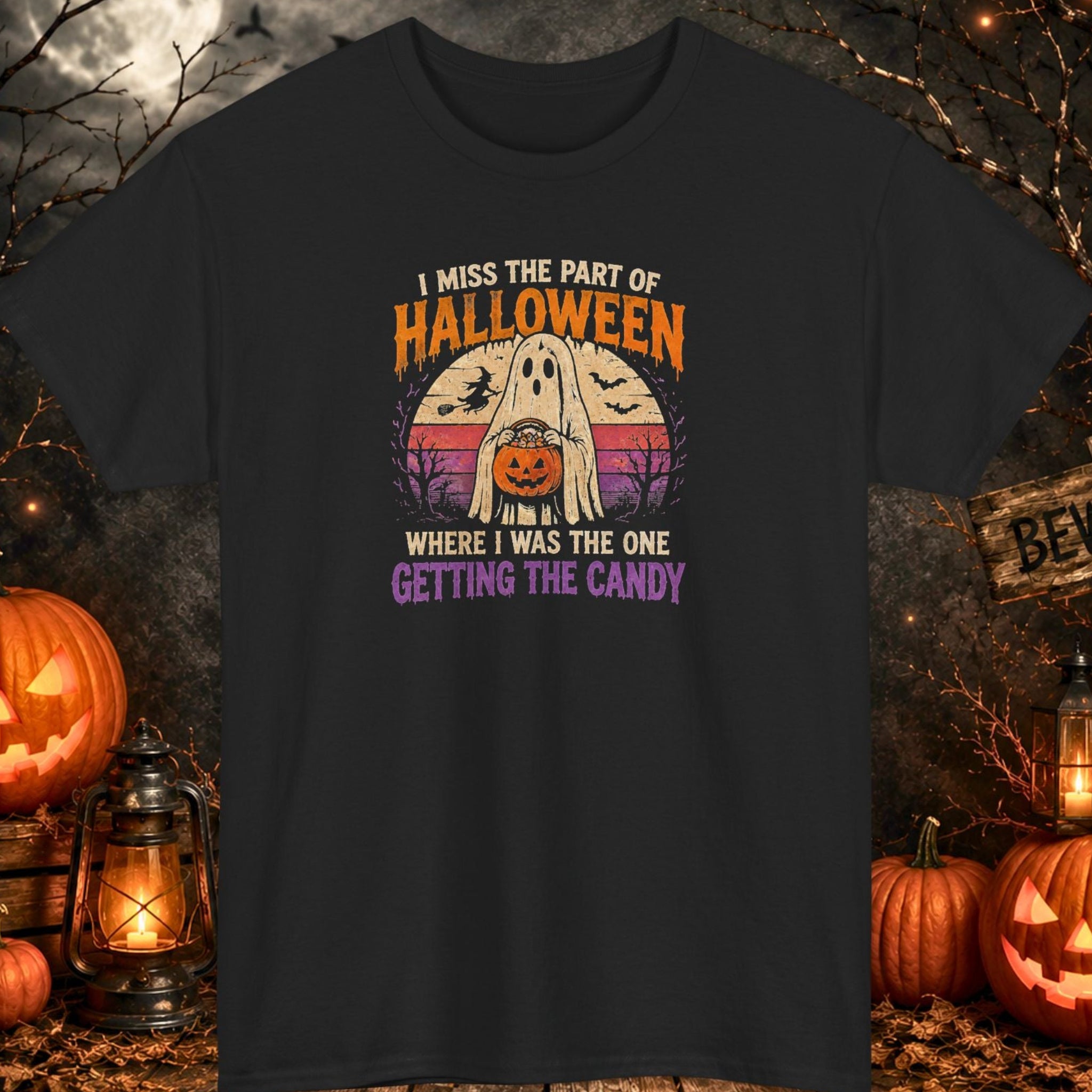 Mayhem Haus black Halloween T-shirt featuring a friendly ghost holding a pumpkin-shaped candy bucket with the phrase, "I Miss the Part of Halloween Where I Was the One Getting the Candy," in distressed retro-style lettering with bats, a witch silhouette, and a vintage sunset background.