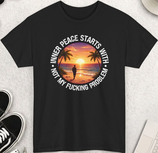 Black t-shirt with a sunset design and text on a light gray surface with shoes, coffee, and sunglasses.