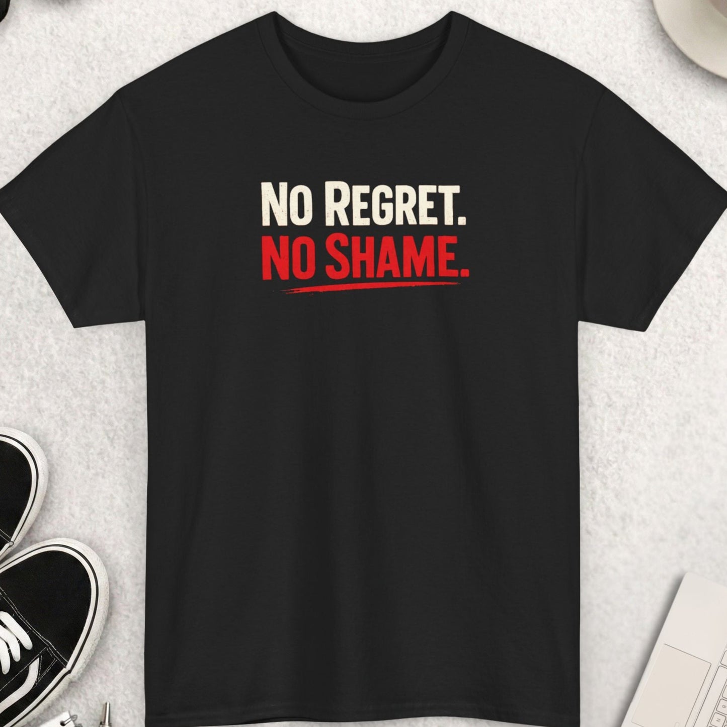 Black t-shirt with 'No Regret. No Shame.' text on a light gray surface with shoes, coffee, and accessories.