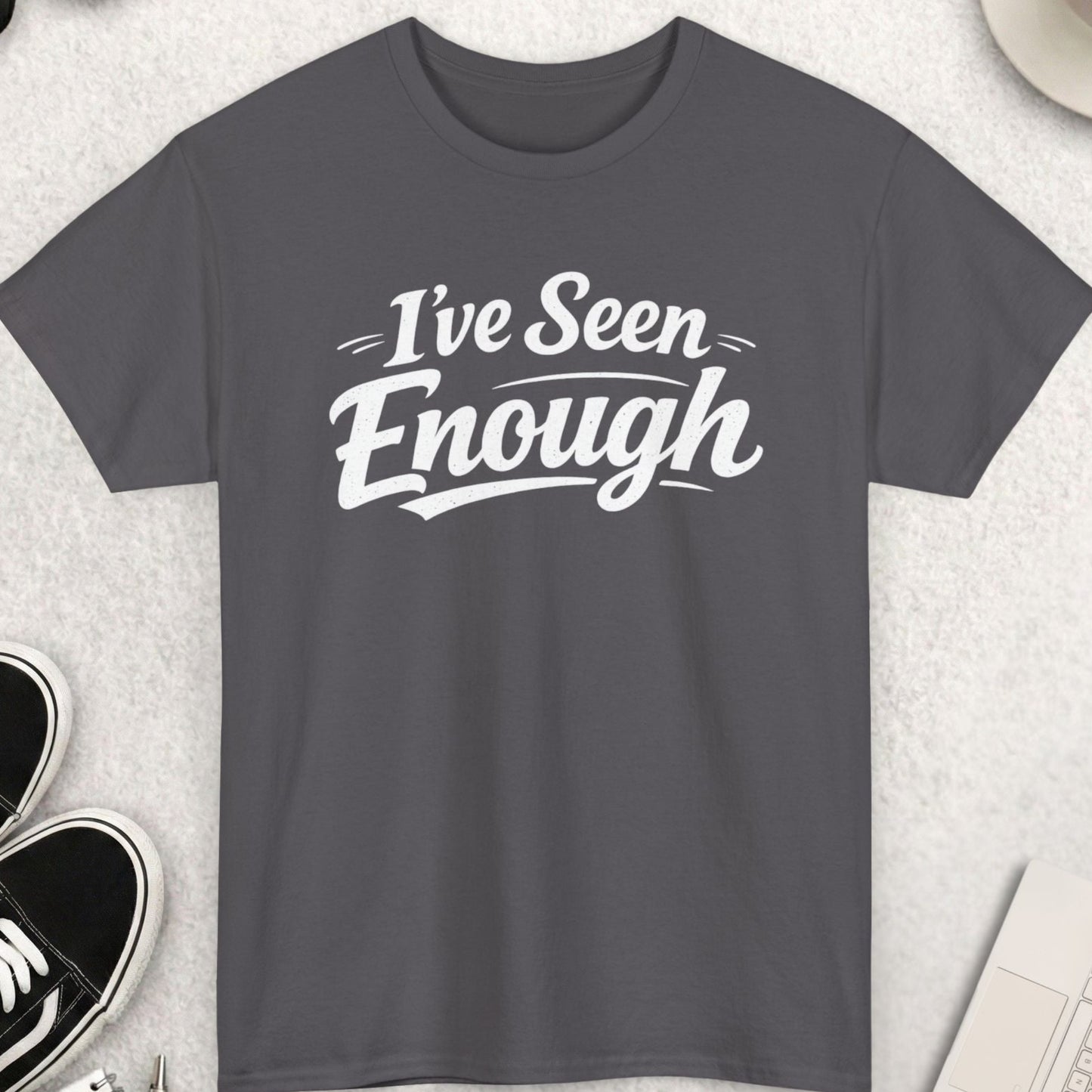 Gray t-shirt with 'I've Seen Enough' text on a light gray surface with accessories.