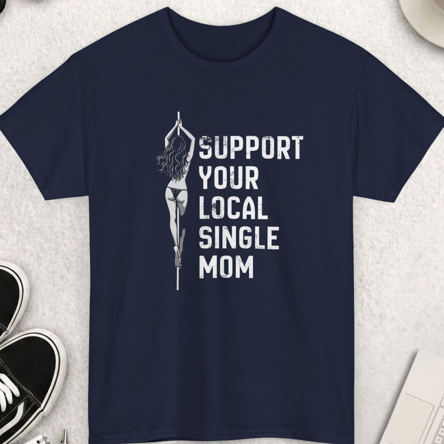 Navy blue t-shirt with 'Support Your Local Single Mom' text on a light gray surface with accessories.
