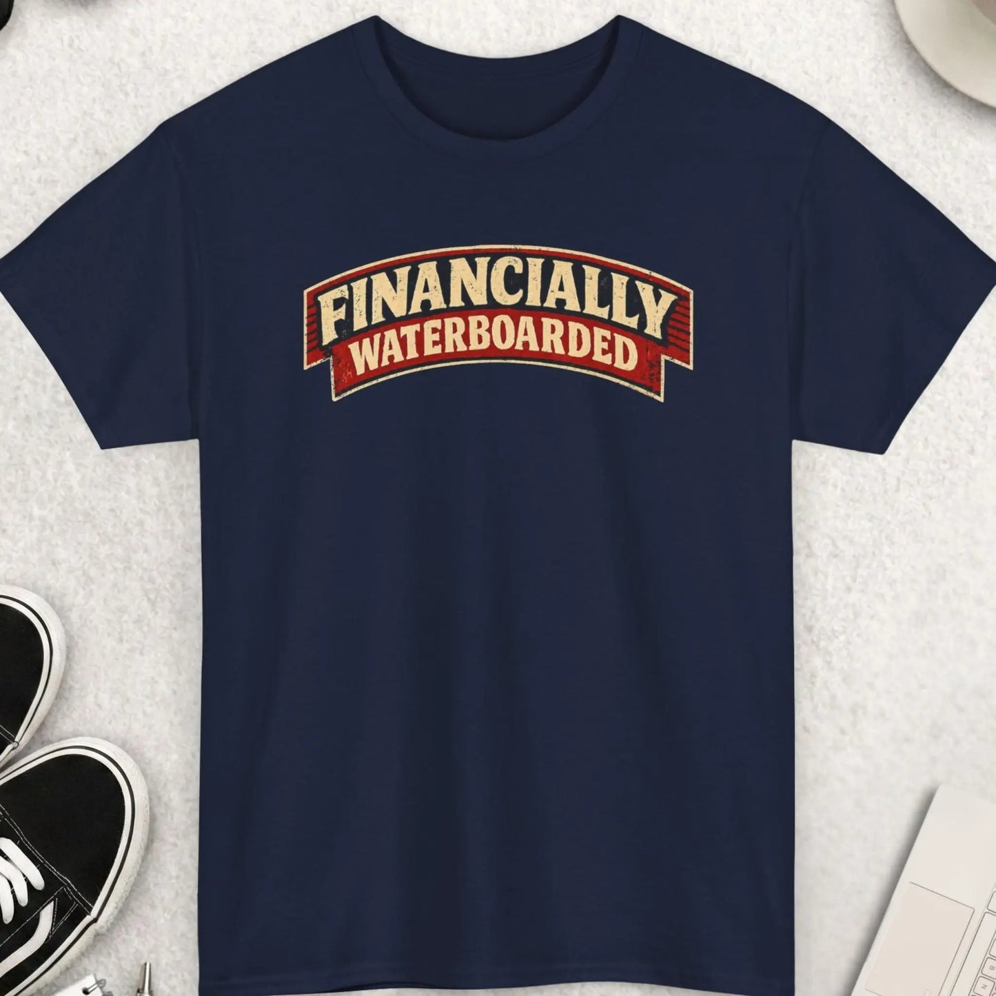 Financially Waterboarded" vintage distressed biker rocker patch style graphic t-shirt on a navy blue background. Cream arched slab serif lettering on a red and dark navy curved rocker banner with a grungy worn texture. Sarcastic financial dark humor debt inflation funny graphic tee.