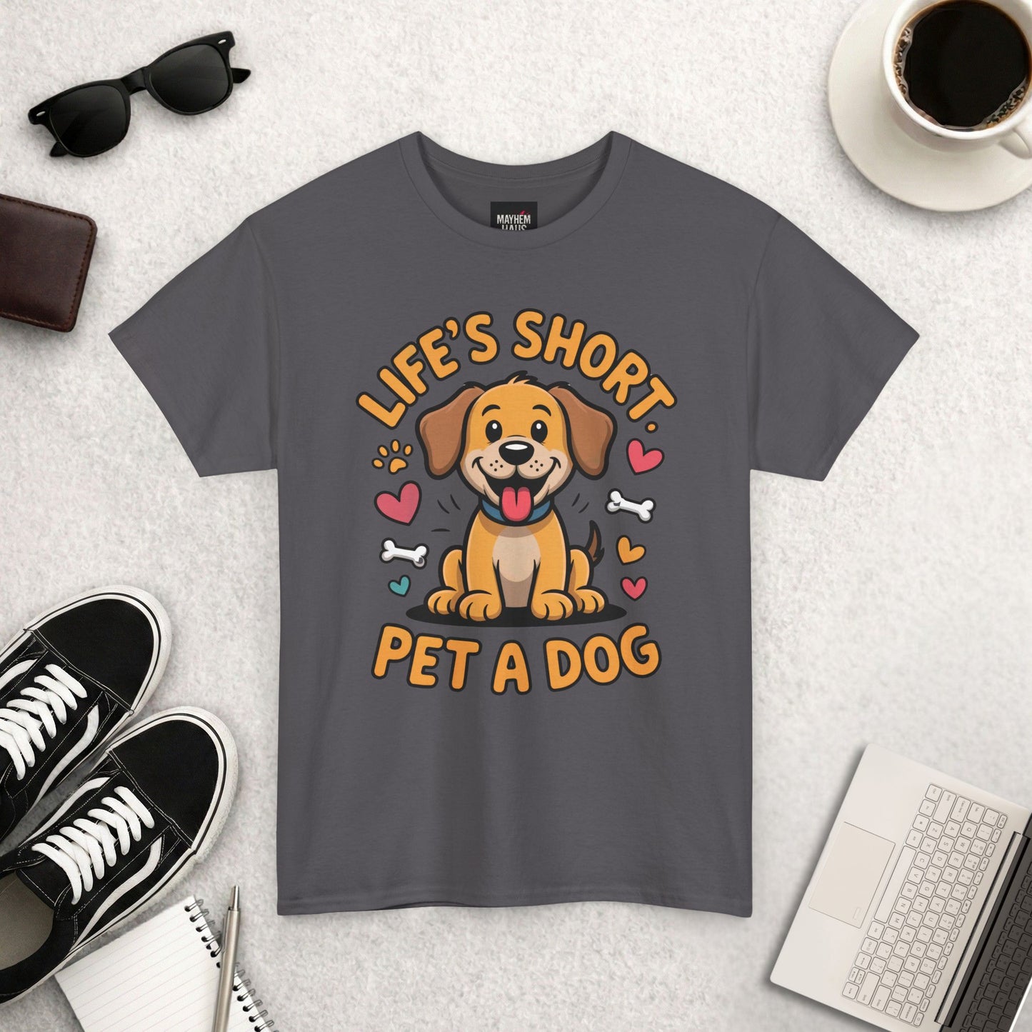 Gray t-shirt with a dog graphic and text on a light gray surface with accessories.