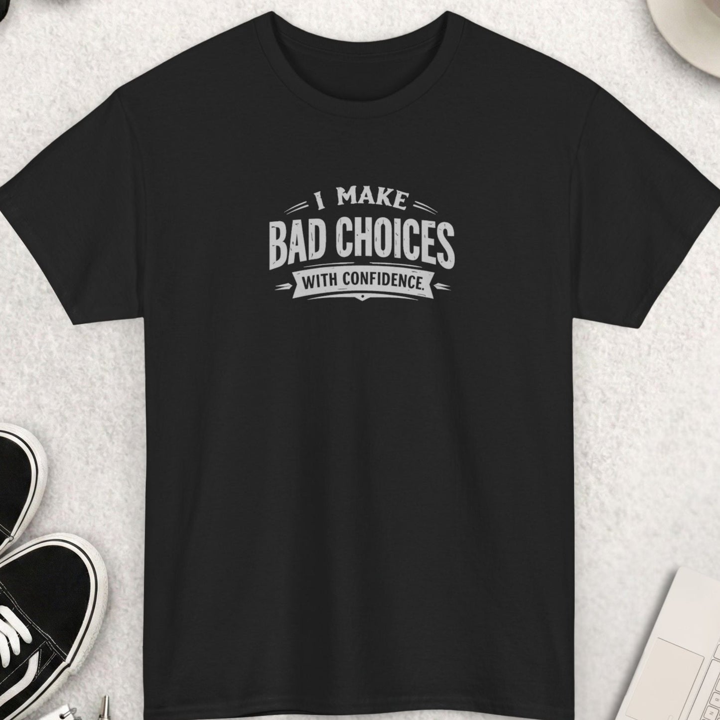 Black t-shirt with 'I Make Bad Choices With Confidence' text on a light gray surface with shoes, coffee, and accessories.