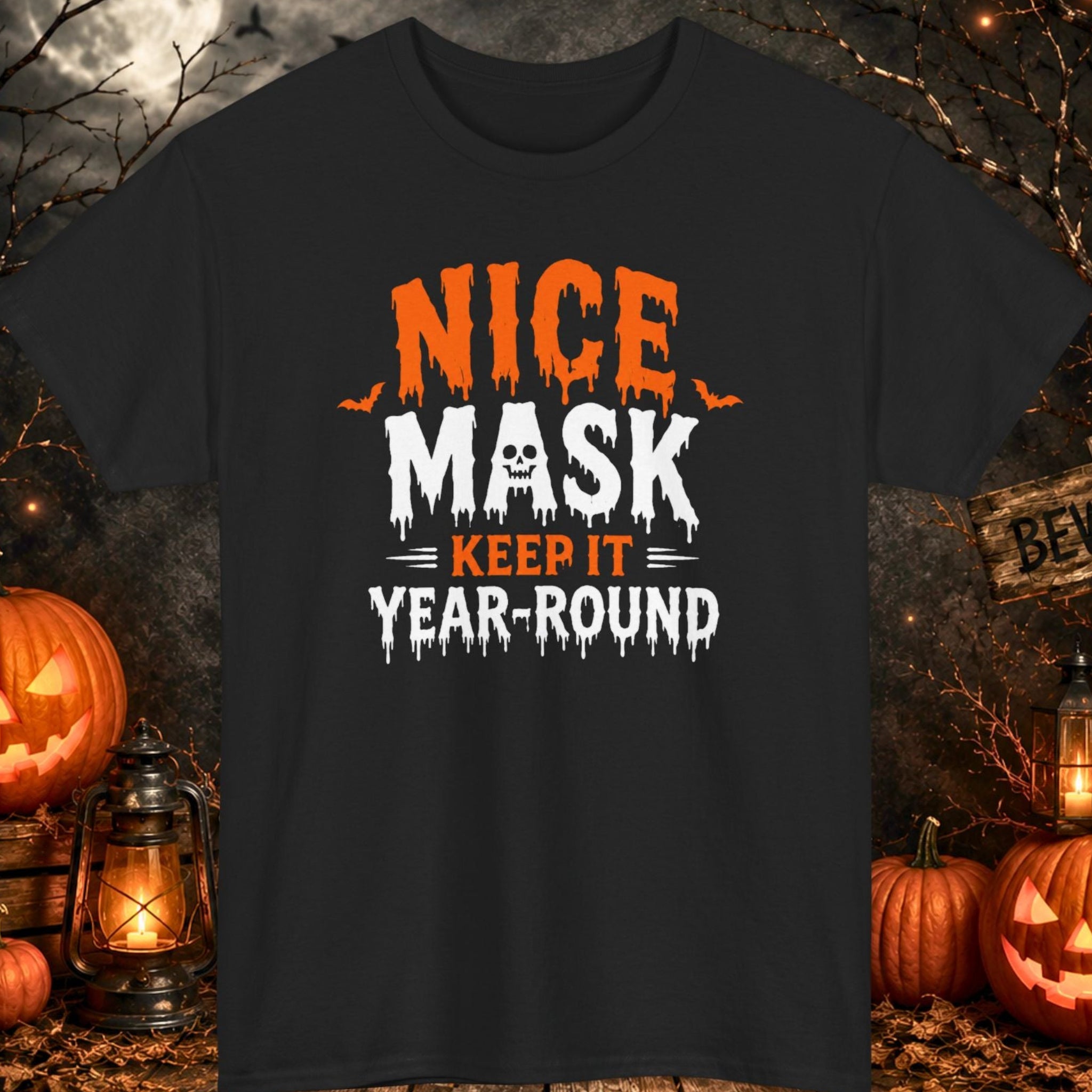 Mayhem Haus Halloween typography t-shirt on a black shirt featuring dripping orange and white lettering reading "Nice Mask Keep It Year-Round" with a skull replacing the letter "A."