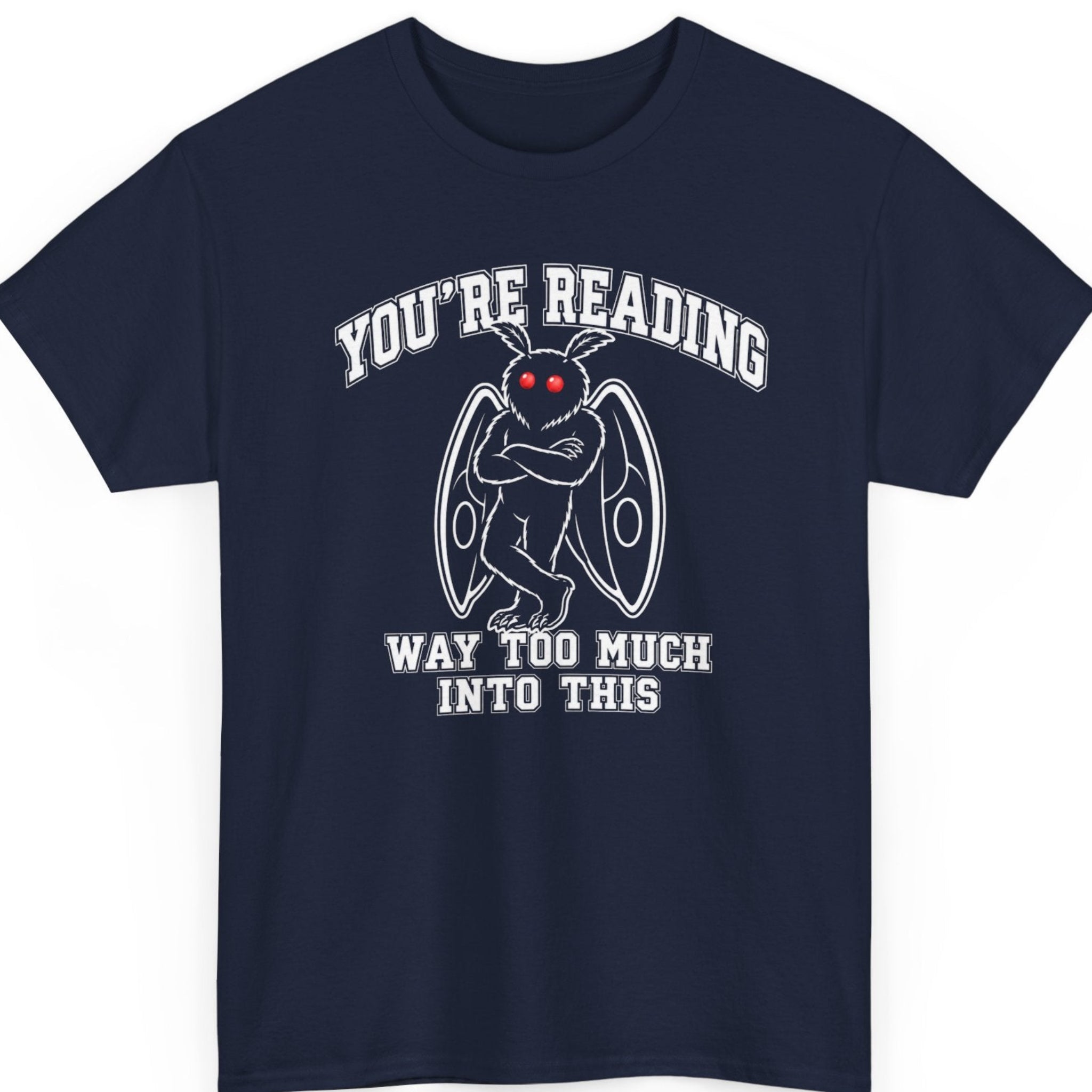 Mayhem Haus cryptid t-shirt on a navy blue shirt featuring a simplified Mothman with bright red glowing eyes, folded wings, and crossed arms paired with bold collegiate lettering that says "YOU'RE READING WAY TOO MUCH INTO THIS."