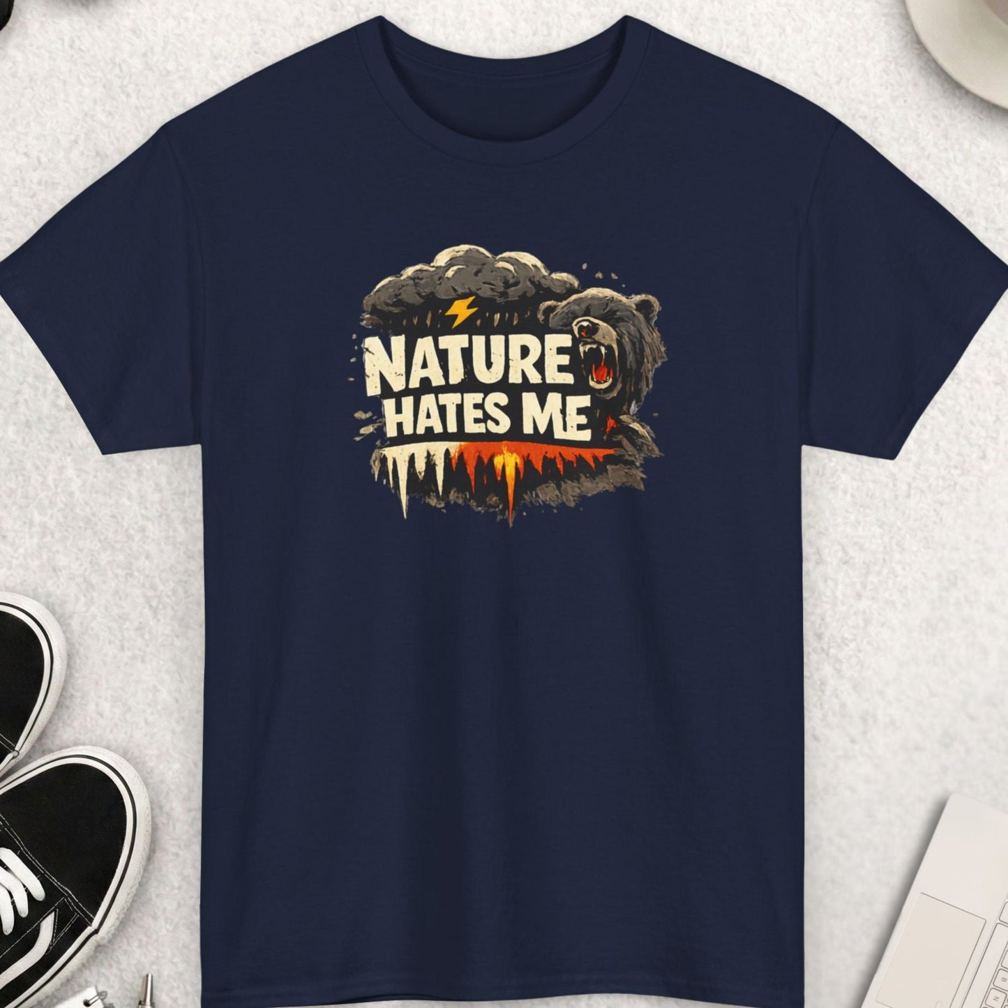 Navy blue t-shirt with 'Nature Hates Me' graphic on a light gray surface with accessories.