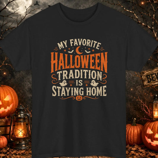 Funny Halloween graphic t-shirt featuring distressed vintage typography reading "My Favorite Halloween Tradition Is Staying Home" with ghost illustrations, bats, crescent moon, and jack-o'-lantern accents on a black shirt, perfect for introverts, homebodies, Halloween lovers, and spooky season fans.