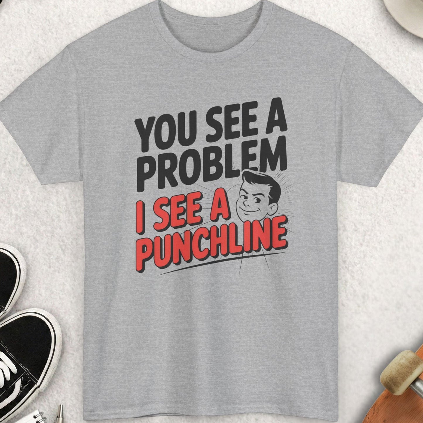 Gray t-shirt with humorous text design on a light gray surface with accessories.