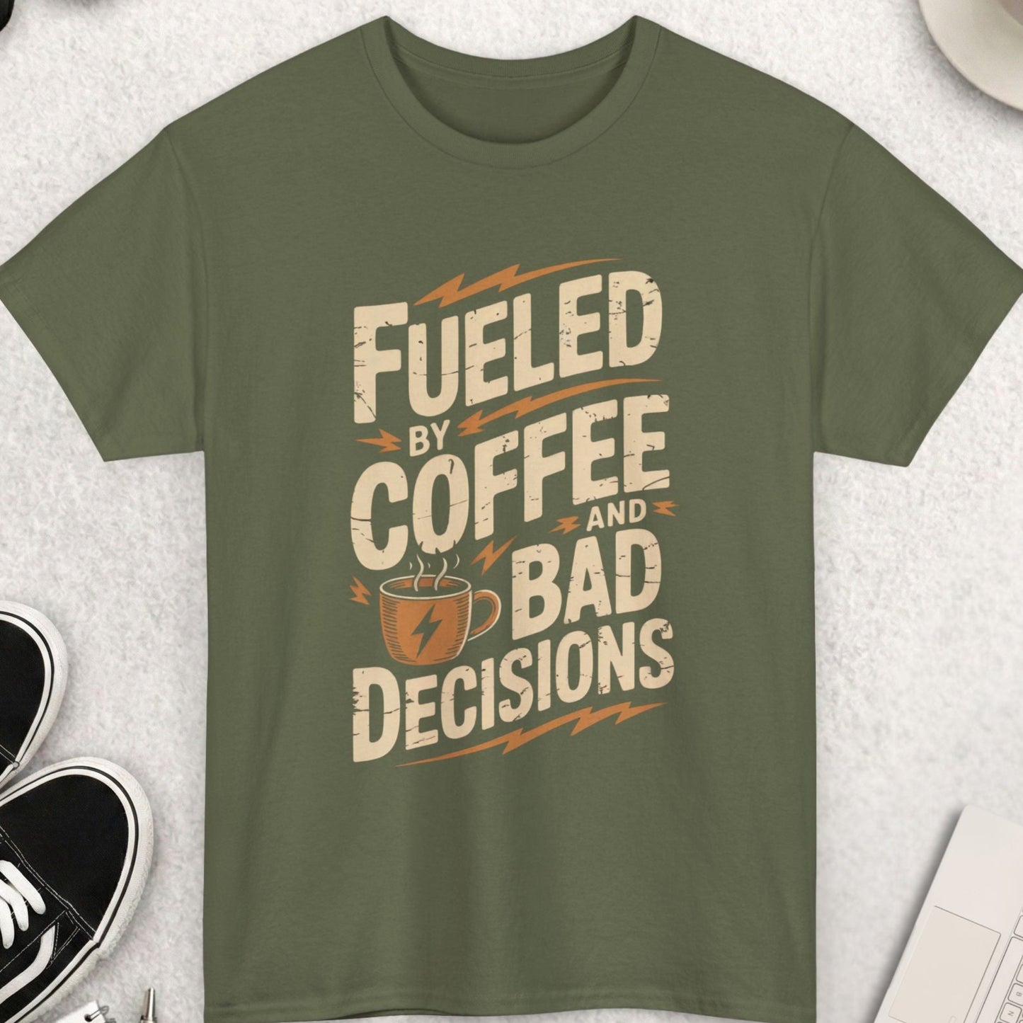 Green t-shirt with 'Fueled by Coffee and Bad Decisions' text on a light gray surface with accessories.