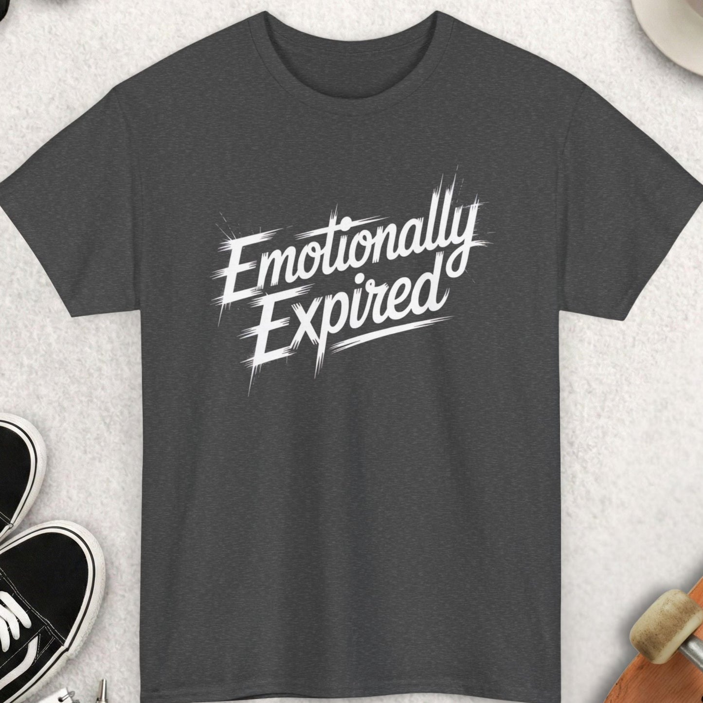 Dark gray t-shirt with 'Emotionally Expired' text on a light gray surface with accessories.