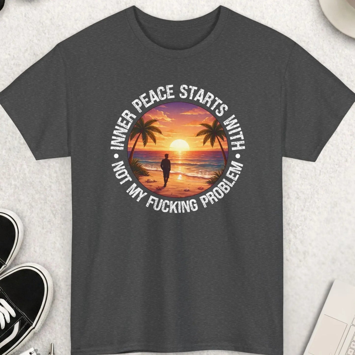 Gray t-shirt with a graphic design and text on a light gray surface with accessories.