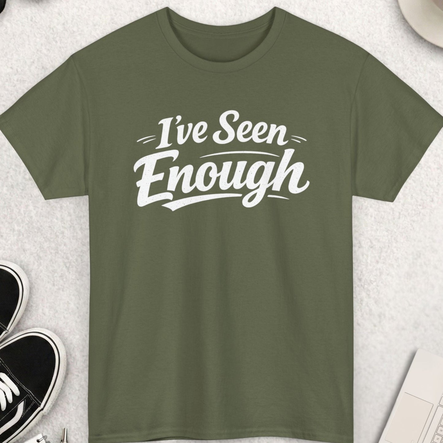 Green t-shirt with 'I've Seen Enough' text on a light gray surface with accessories.