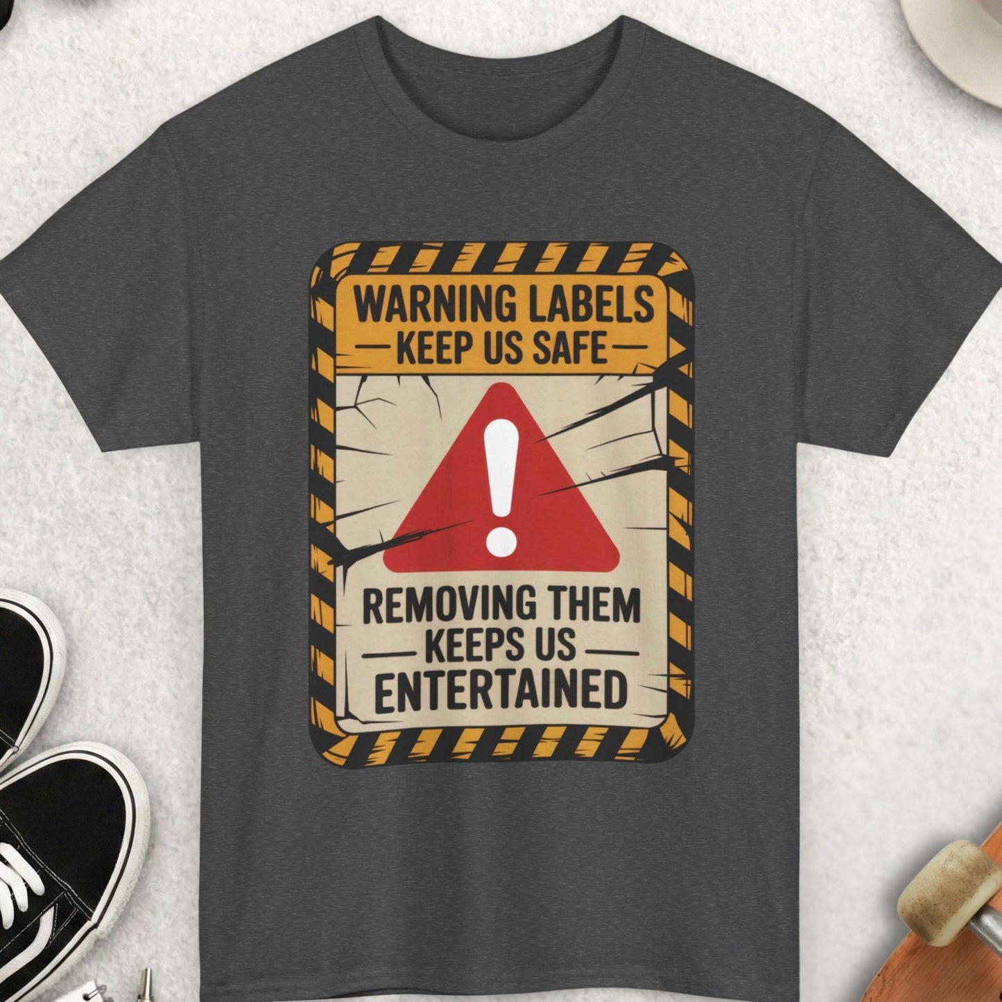 Gray t-shirt with a warning label design on a light gray surface with accessories.