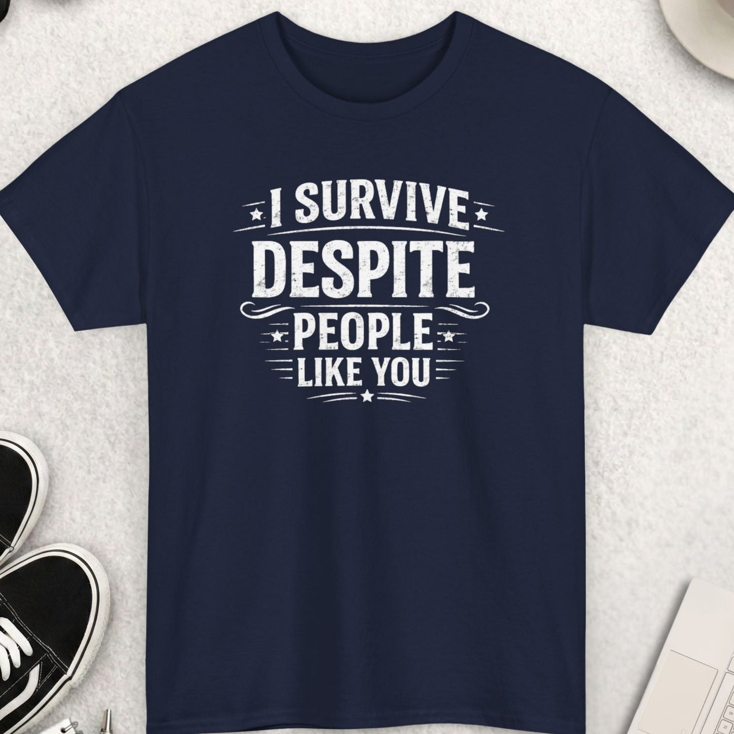 Navy blue t-shirt with humorous text design on a light gray surface with accessories.