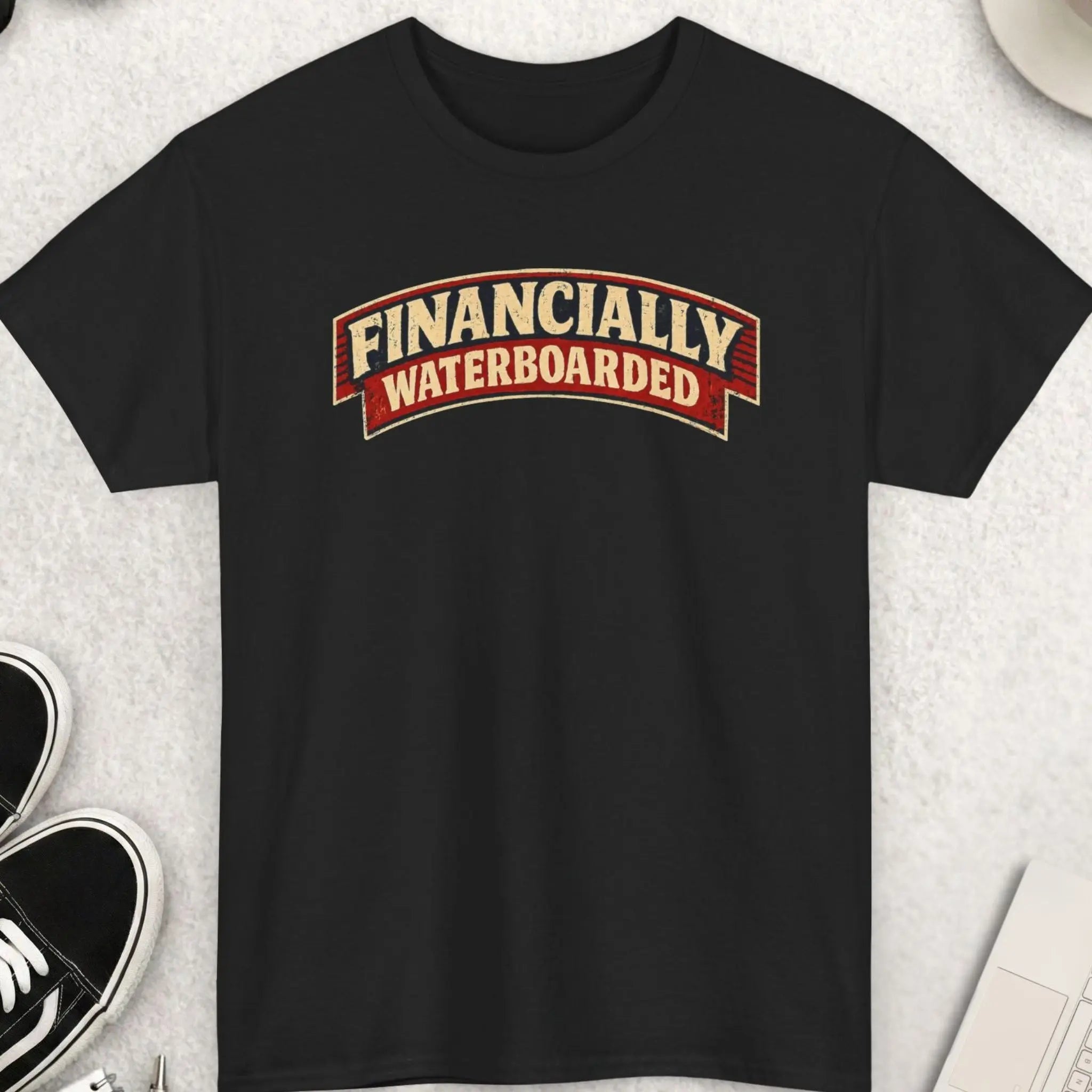 Financially Waterboarded" vintage distressed biker rocker patch graphic t-shirt on a black background. Bold cream arched serif slab typography on a deep red and navy curved banner with a weathered, aged distressed texture. Funny dark humor sarcastic broke life inflation money statement tee.