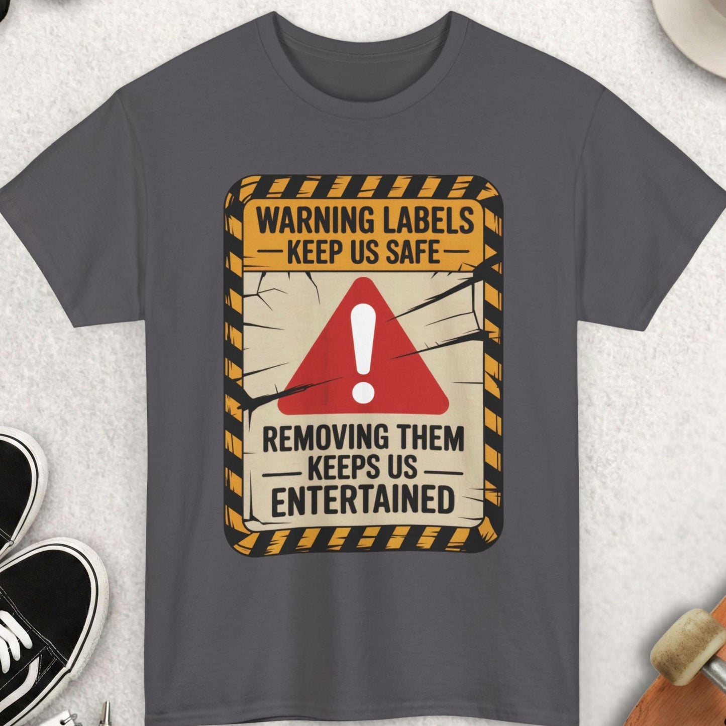 Gray t-shirt with a warning label design on a light gray surface with accessories.