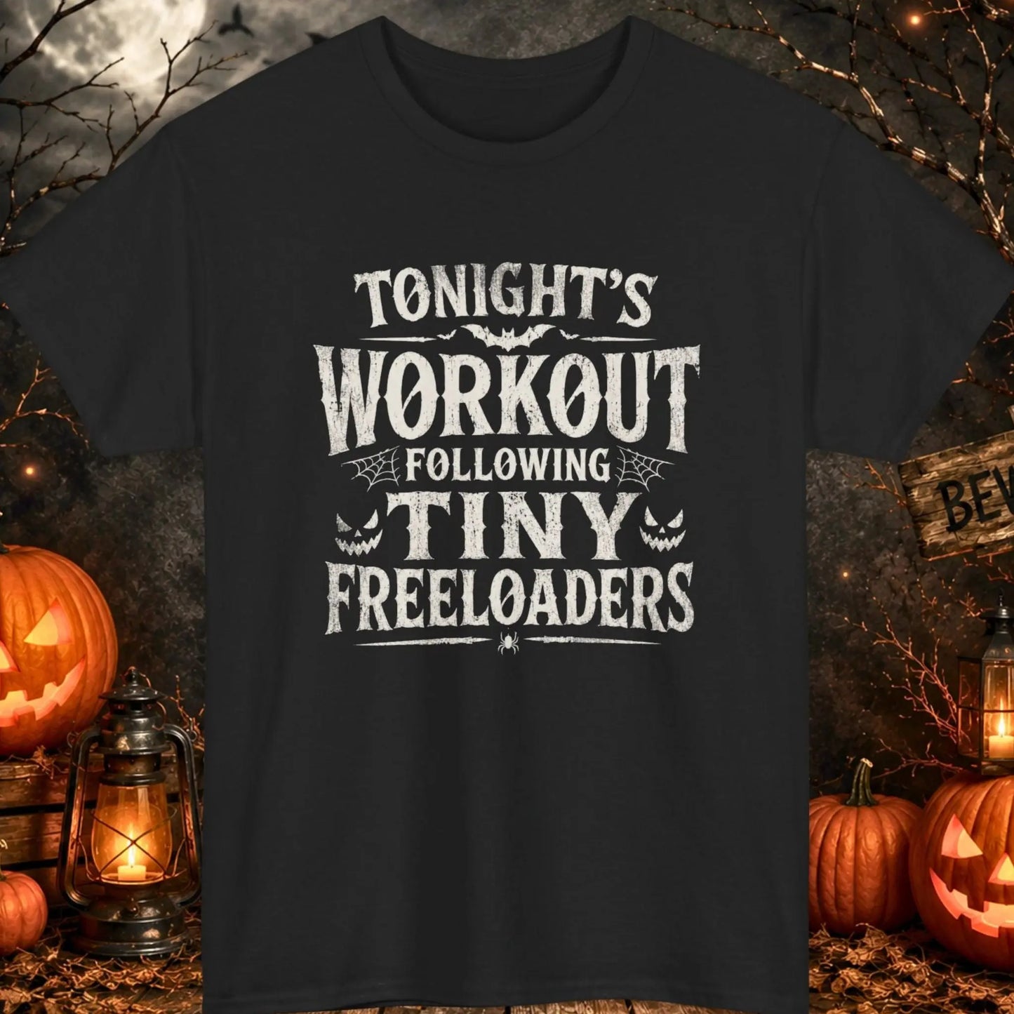Funny Halloween graphic t-shirt featuring distressed vintage typography reading "Tonight's Workout Following Tiny Freeloaders" with spider webs, bats, jack-o'-lantern faces, and spooky Halloween accents printed on a black shirt, perfect for parents supervising trick-or-treating and Halloween festivities.