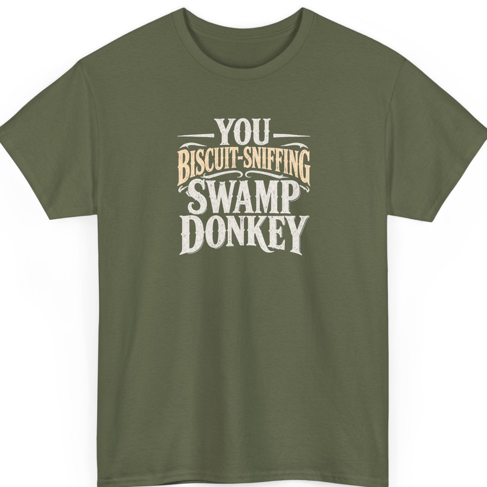 Mayhem Haus “You Biscuit-Sniffing Swamp Donkey” military green t-shirt featuring bold distressed cream and tan typography with decorative Western-style accents.