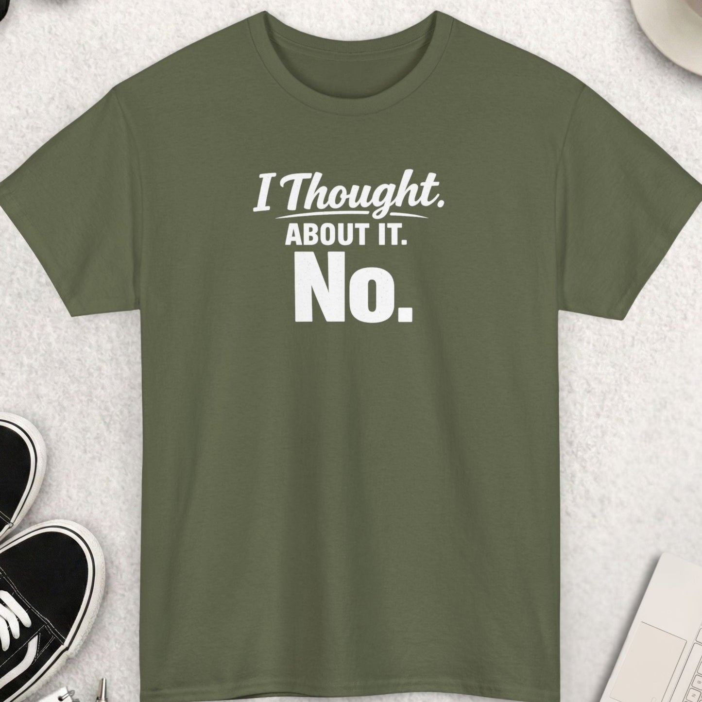 Green t-shirt with 'I Thought About It. No.' text on a light gray surface with accessories.