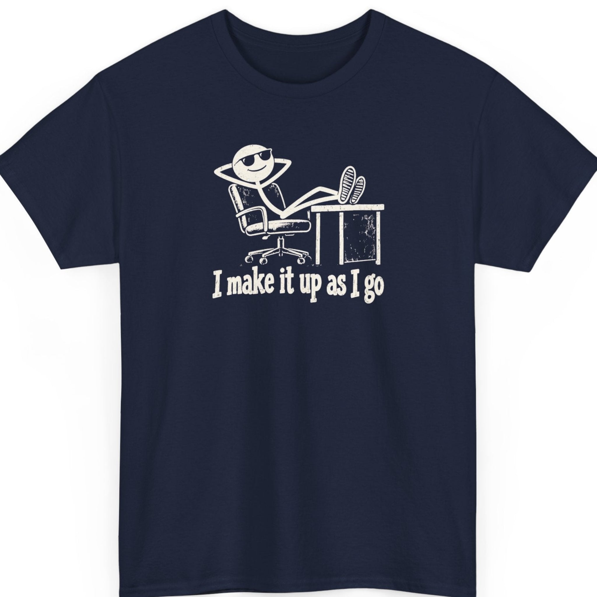 Mayhem Haus “I Make It Up As I Go” navy blue t-shirt featuring a relaxed cartoon stick figure wearing sunglasses and lounging at an office desk, with distressed white typography beneath the illustration.