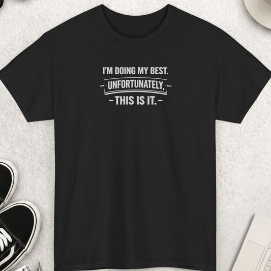 Black t-shirt with humorous text on a light gray surface with shoes, coffee, and accessories.