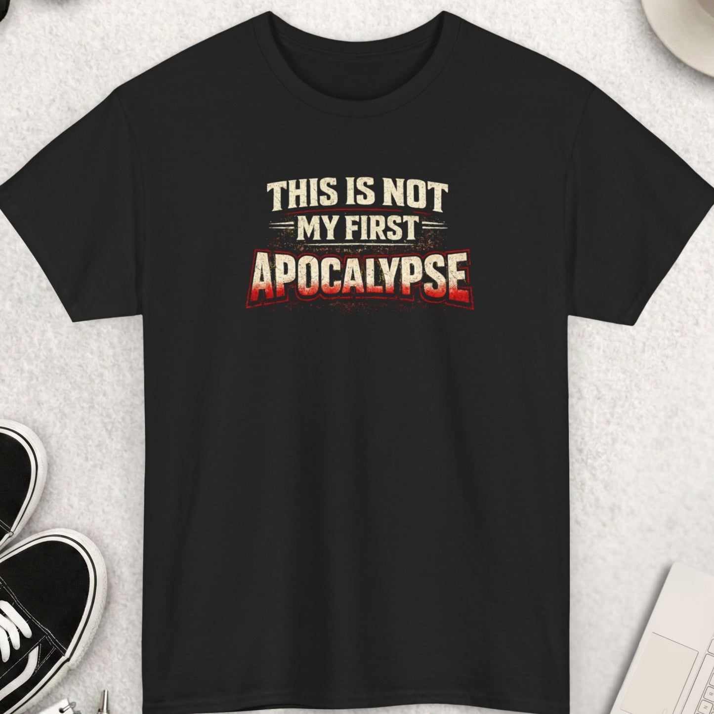 Black graphic t-shirt featuring distressed text that reads “This Is Not My First Apocalypse” in white and red lettering, centered on the chest.