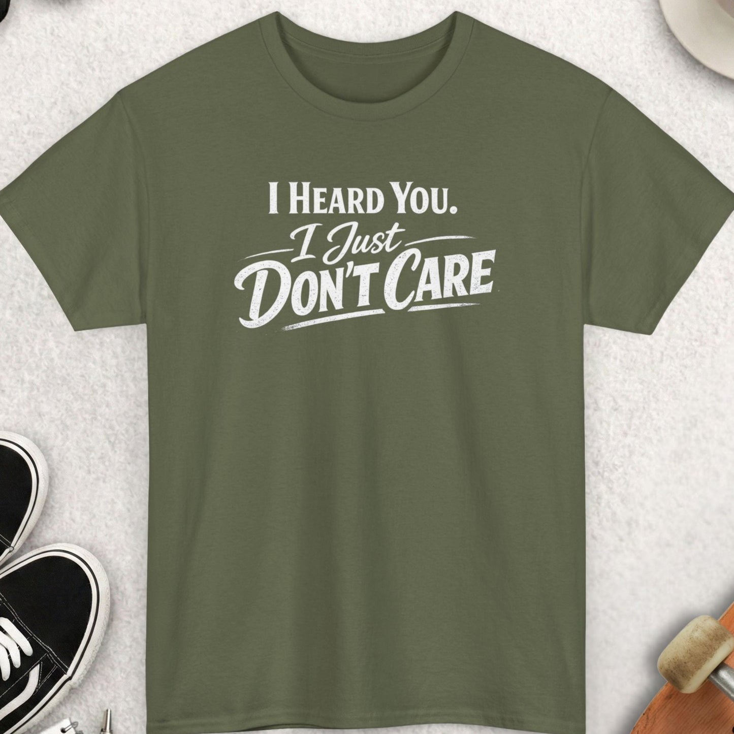 Green t-shirt with 'I Heard You, I Just Don't Care' text on a light gray surface with accessories.