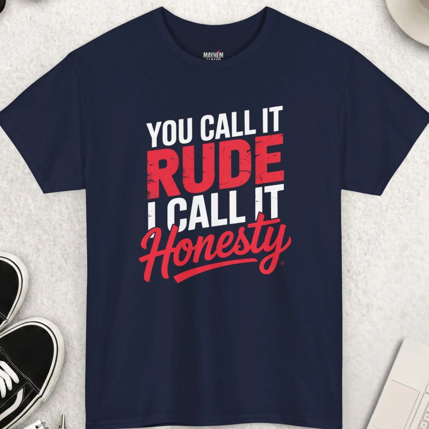 Navy blue t-shirt with text 'You call it rude, I call it honesty' on a light gray surface with accessories.