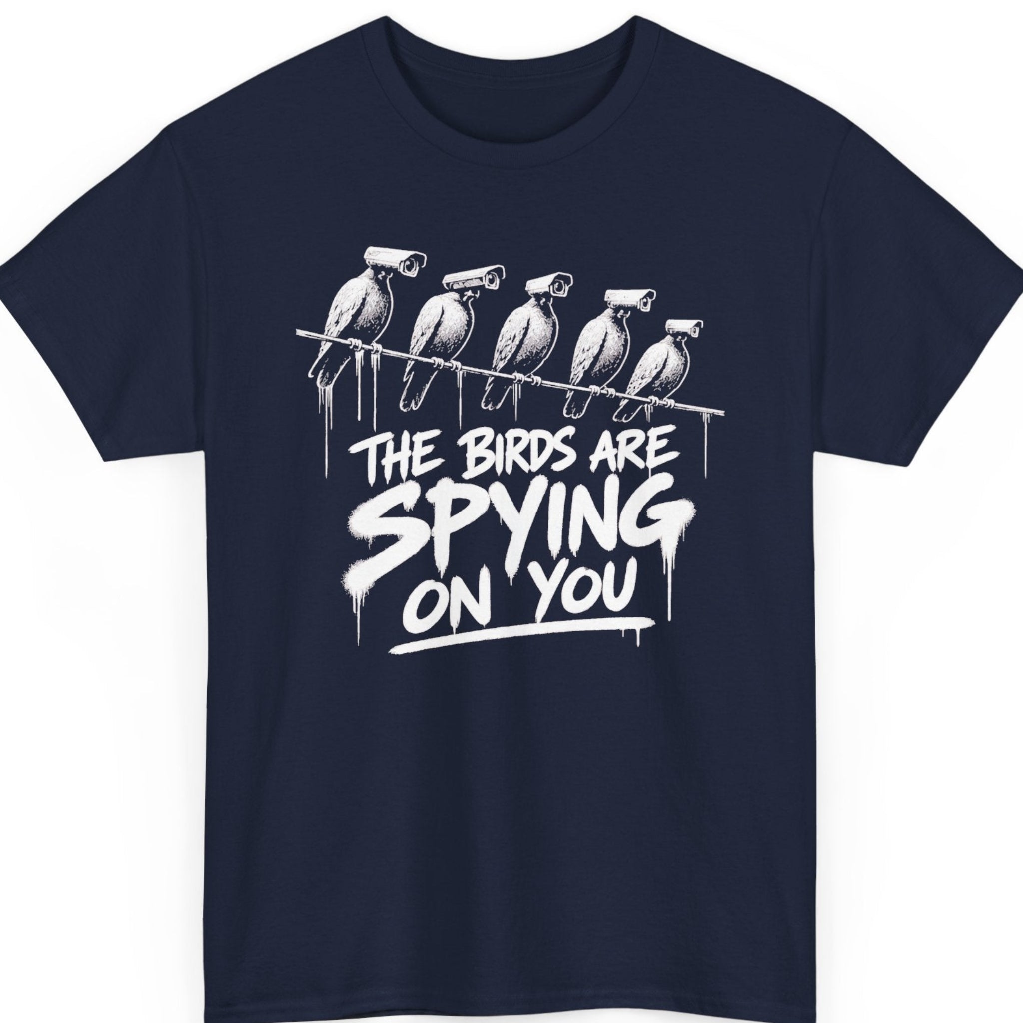 Mayhem Haus funny conspiracy t-shirt on a navy blue tee featuring illustrated surveillance birds with camera heads and bold street-art typography that reads, “The Birds Are Spying On You.”