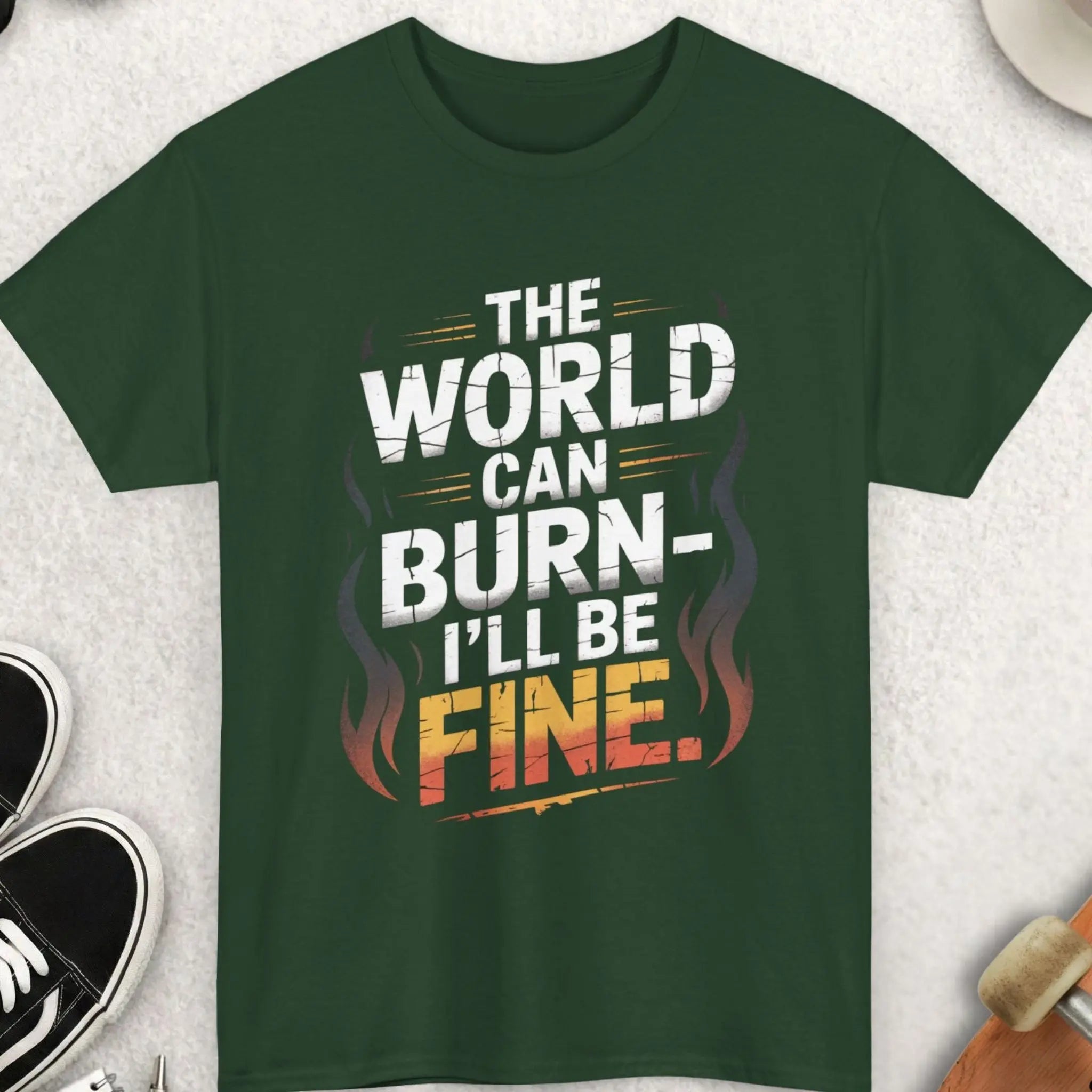 Green t-shirt with 'The World Can Burn, I'll Be Fine' text on a light gray surface with accessories.