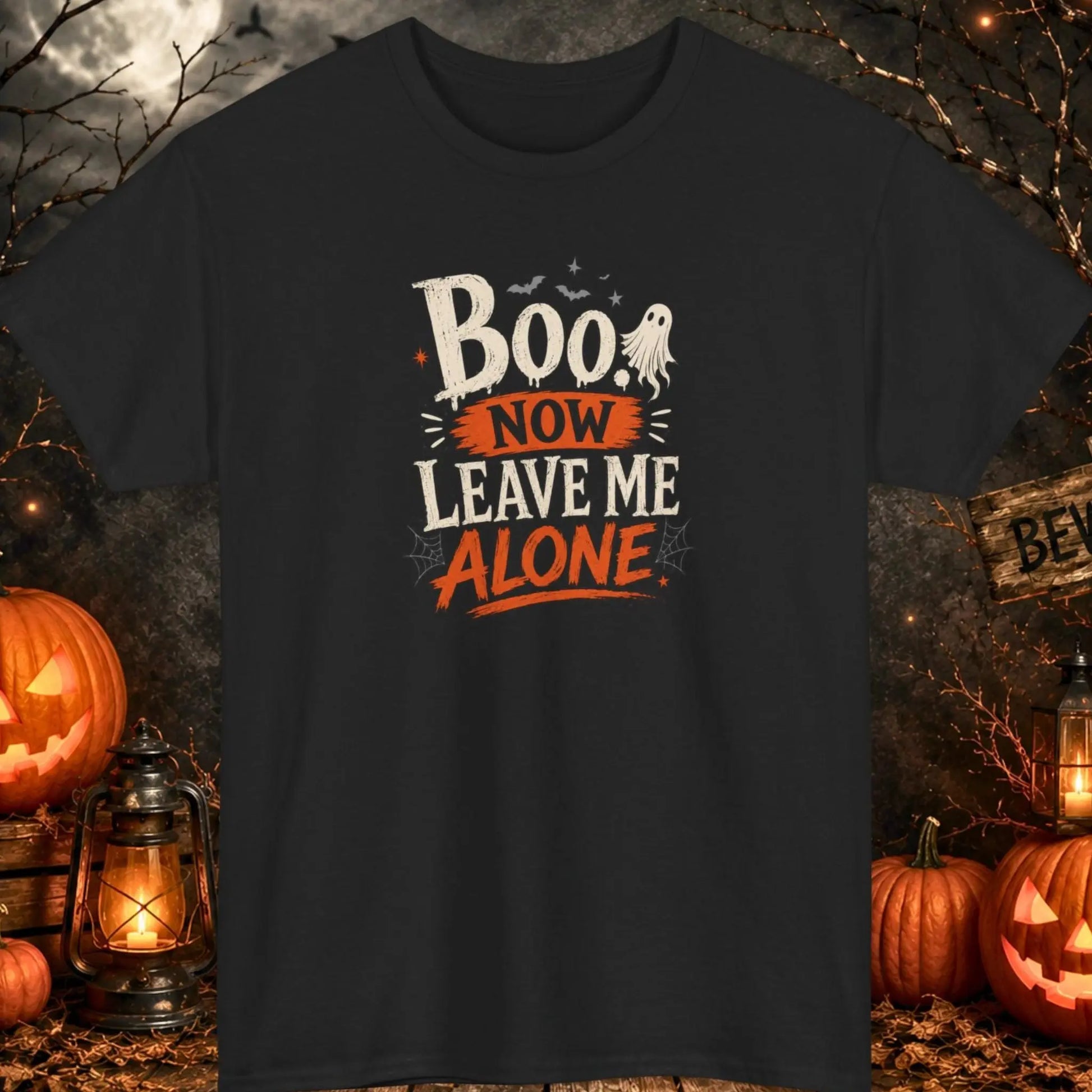 Funny Halloween graphic t-shirt featuring distressed typography reading "Boo. Now Leave Me Alone" with a cute ghost, bats, stars, and spider webs on a black shirt, perfect for introverts, Halloween lovers, spooky season, and sarcastic humor fans.
