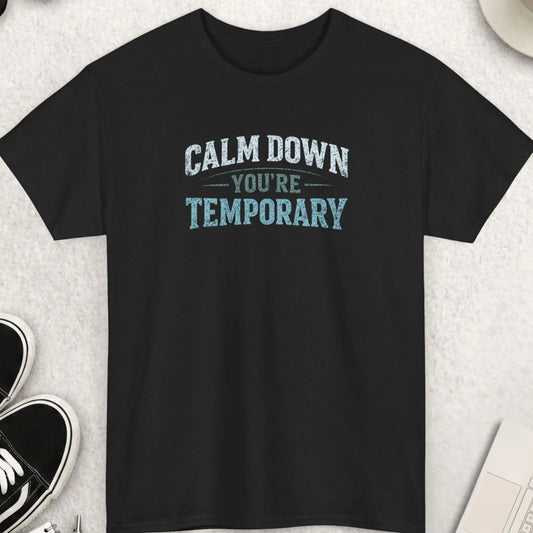 Black t-shirt featuring distressed vintage typography reading “Calm Down You’re Temporary” in a minimalist existential humor design.