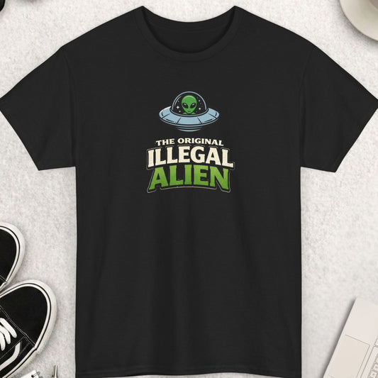 Black t-shirt with 'illegal alien' text on a light gray surface with shoes, sunglasses, and a cup.