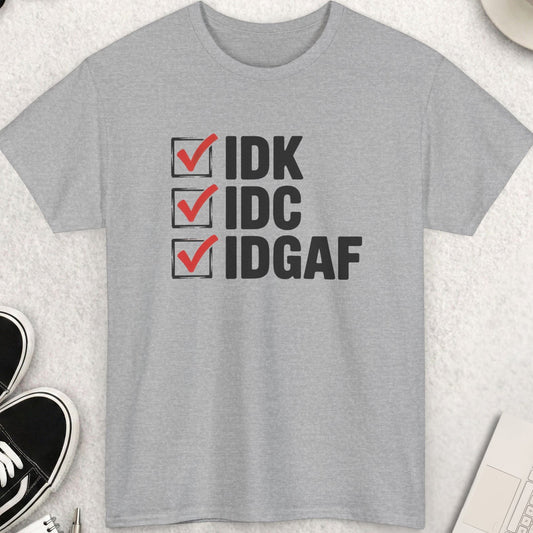 Gray t-shirt with 'IDK IDCIDGAF' text on a light surface with shoes, coffee, and accessories.