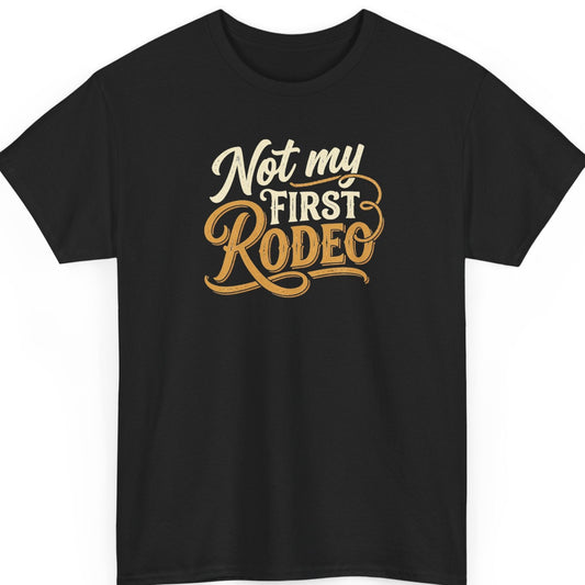 Mayhem Haus “Not My First Rodeo” black t-shirt featuring vintage Western typography in cream and golden tan, with decorative flourishes, flowing script lettering, and a subtly distressed finish.