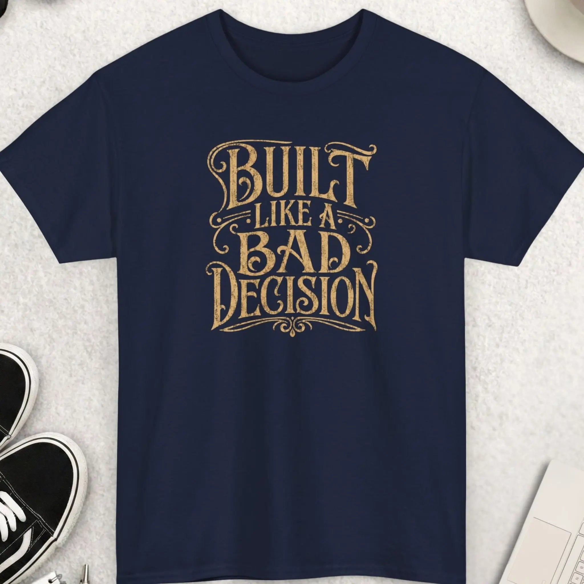 Navy blue vintage distressed typography t-shirt featuring the phrase “Built Like A Bad Decision” in retro western cream-colored lettering with a rugged worn print aesthetic.