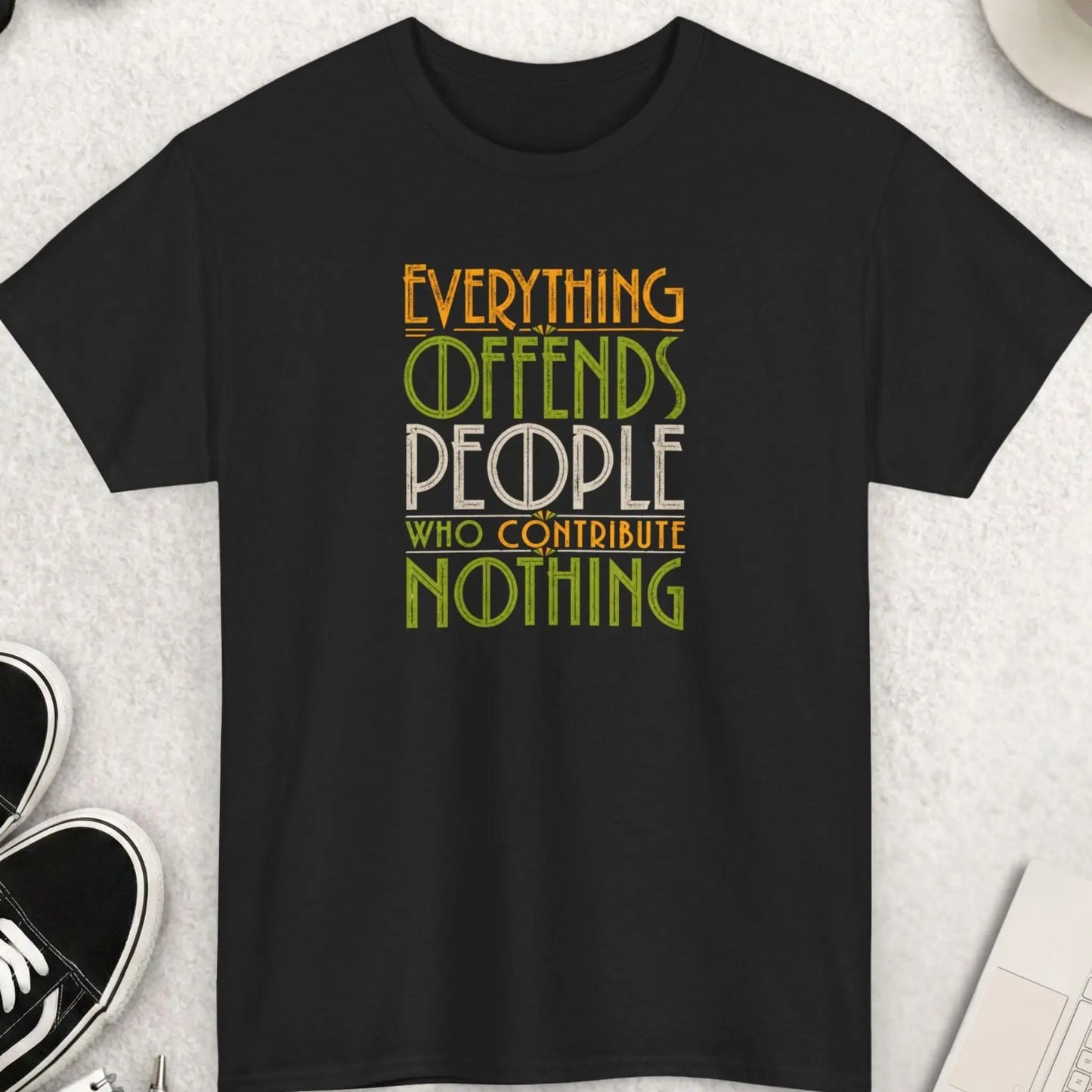 Black vintage typography graphic t-shirt featuring the phrase “Everything Offends People Who Contribute Nothing” in distressed green, gold, and cream retro lettering with a bold statement aesthetic.