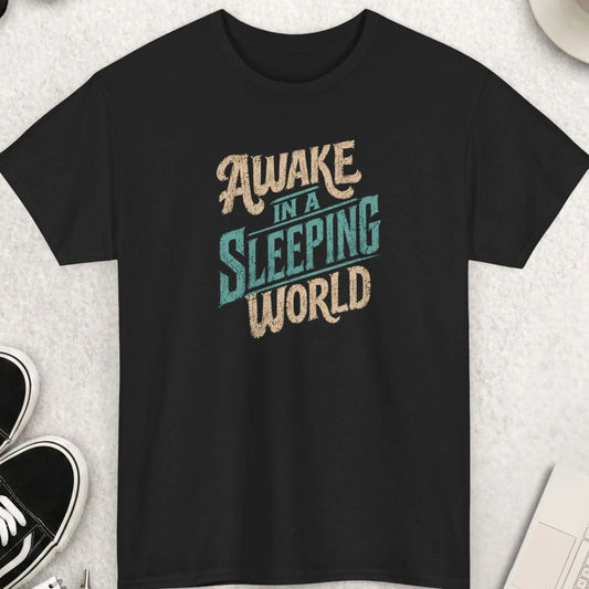 Awake In A Sleeping World distressed typography t-shirt design featuring large vintage cream and retro blue text on a black shirt with weathered texture and bold statement message.